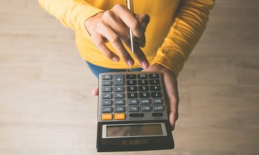 une femme entrant des chiffres dans la calculatrice pour calculer l’augmentation de loyer