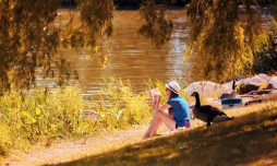 Une jeune adolescente lit un livre au bord de la rivière dans le parc des rapides de Lachine.