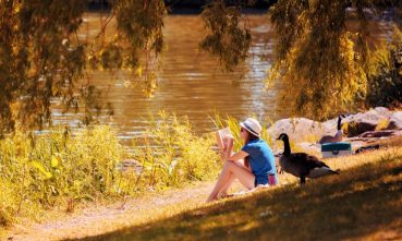 Une jeune adolescente lit un livre au bord de la rivière dans le parc des rapides de Lachine.